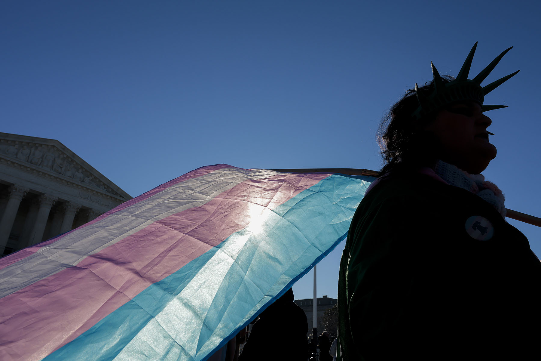 A person holds a transgender pride flag as they protest outside the Supreme Court in Washington, D.C