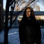 A portrait of Katie Paris standing on a wintery street, her face half in shadow.
