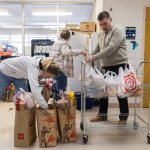 People pack bags of groceries inside a school.