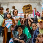 A group of people hold signs and trans flags.