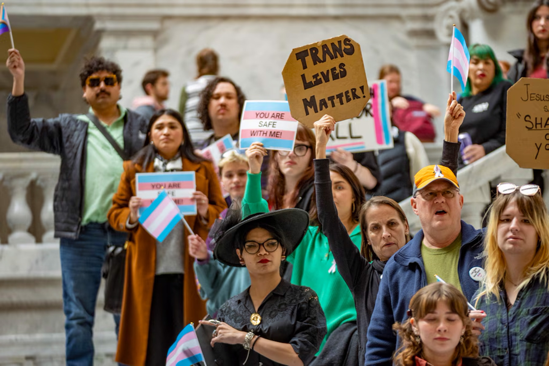A group of people hold signs and trans flags.