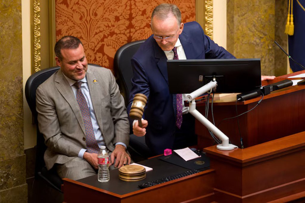 Two politicians in suits appear to preside over a room.
