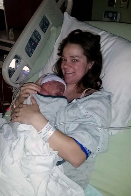Mother holds newborn in a hospital bed.