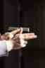 Close-up of a person’s hands holding a handgun, with fingers extended alongside the frame rather than on the trigger.