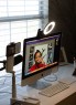 A desktop computer setup with a ring light and phone mount shows a video call in progress.
