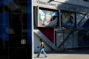 A person walks past a building with a sign reading “Cesar Chavez Student Center,” with painted murals of Cesar Chavez and Malcolm X on the wall above.