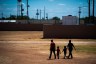 Immigrant woman and children walk across a field as U.S. Immigration and Customs Enforcement hosts a media tour at the South Texas Family Residential Center in Dilley, Texas.