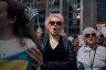A young woman with pink hair chants during a protest, surrounded by other women.