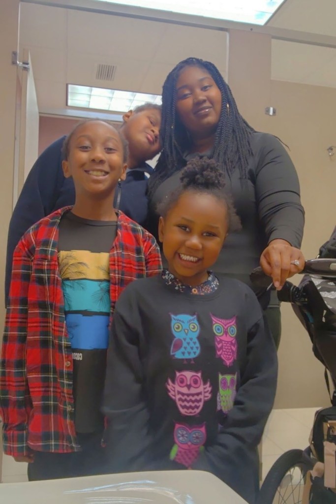 A woman stands with four children gathered around her, all smiling at the camera.