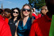 Jocelyn Benson wearing sunglasses stands in a crowd at an outdoor event, with people around her in bright daylight.