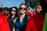 Jocelyn Benson wearing sunglasses stands in a crowd at an outdoor event, with people around her in bright daylight.
