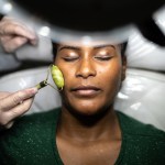 A woman receives a facial massage with a crystal roller under a light.