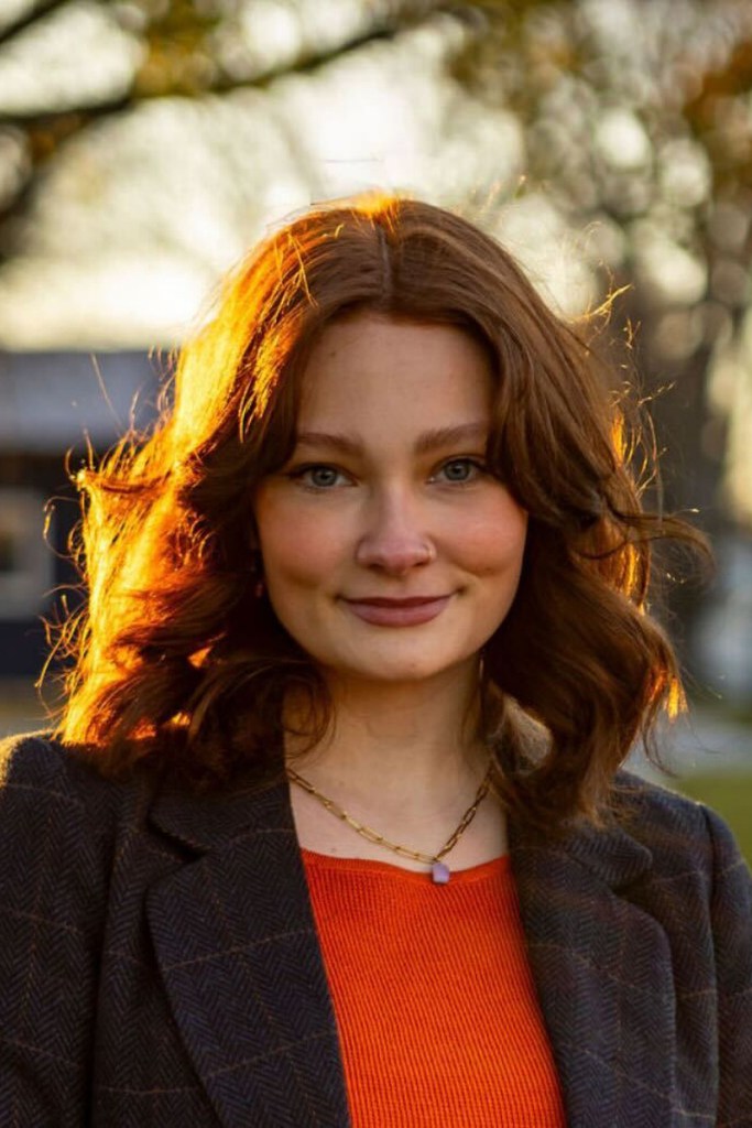 A head and shoulders portrait of a woman backlit by the sun.