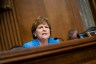 Shaheen seated at a desk in a blue suit.