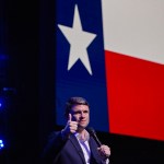 Talarico gives a thumbs up while standing in front of a giant Texas flag.
