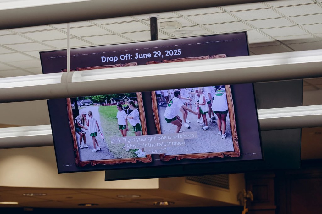 A screen in a committee hearing room shows photos of Camp Mystic campers and counselors, including a slide dated June 29, 2025, with a quoted message from Dick Eastland.