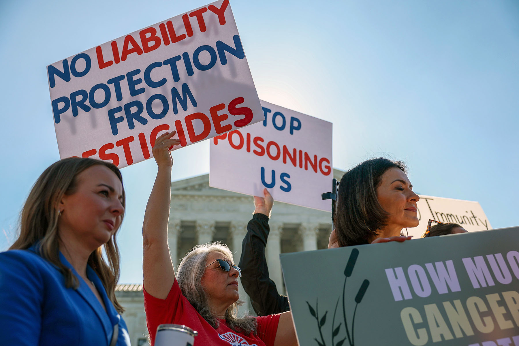 Protesters stand outside the U.S. Supreme Court holding signs that read “No liability protection from pesticides,” and “Stop poisoning us.”
