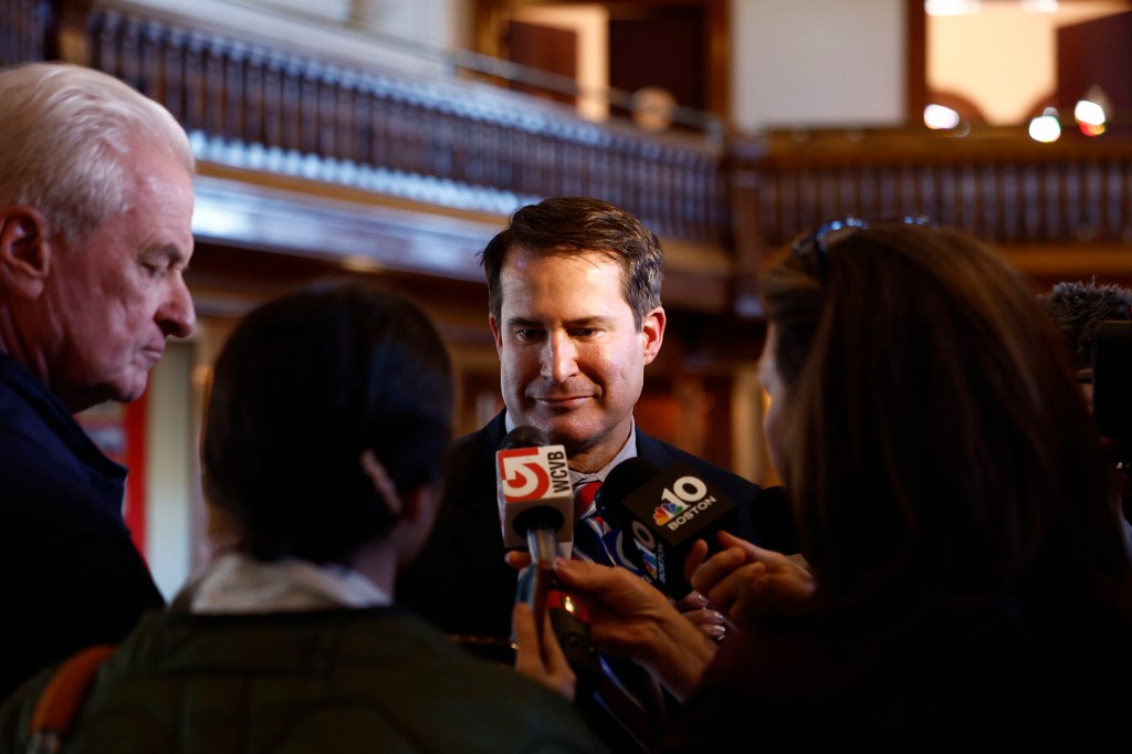 Rep. Seth Moulton speaks with reporters holding microphones and phones.