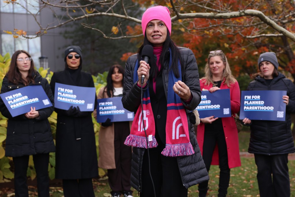Johnson stands in front of a group of women speaking while those behind her hold signs.