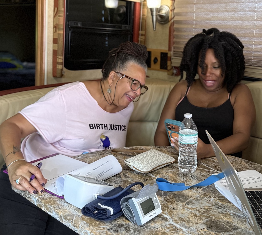 Two women sit at a table talking during a pregnancy checkup.
