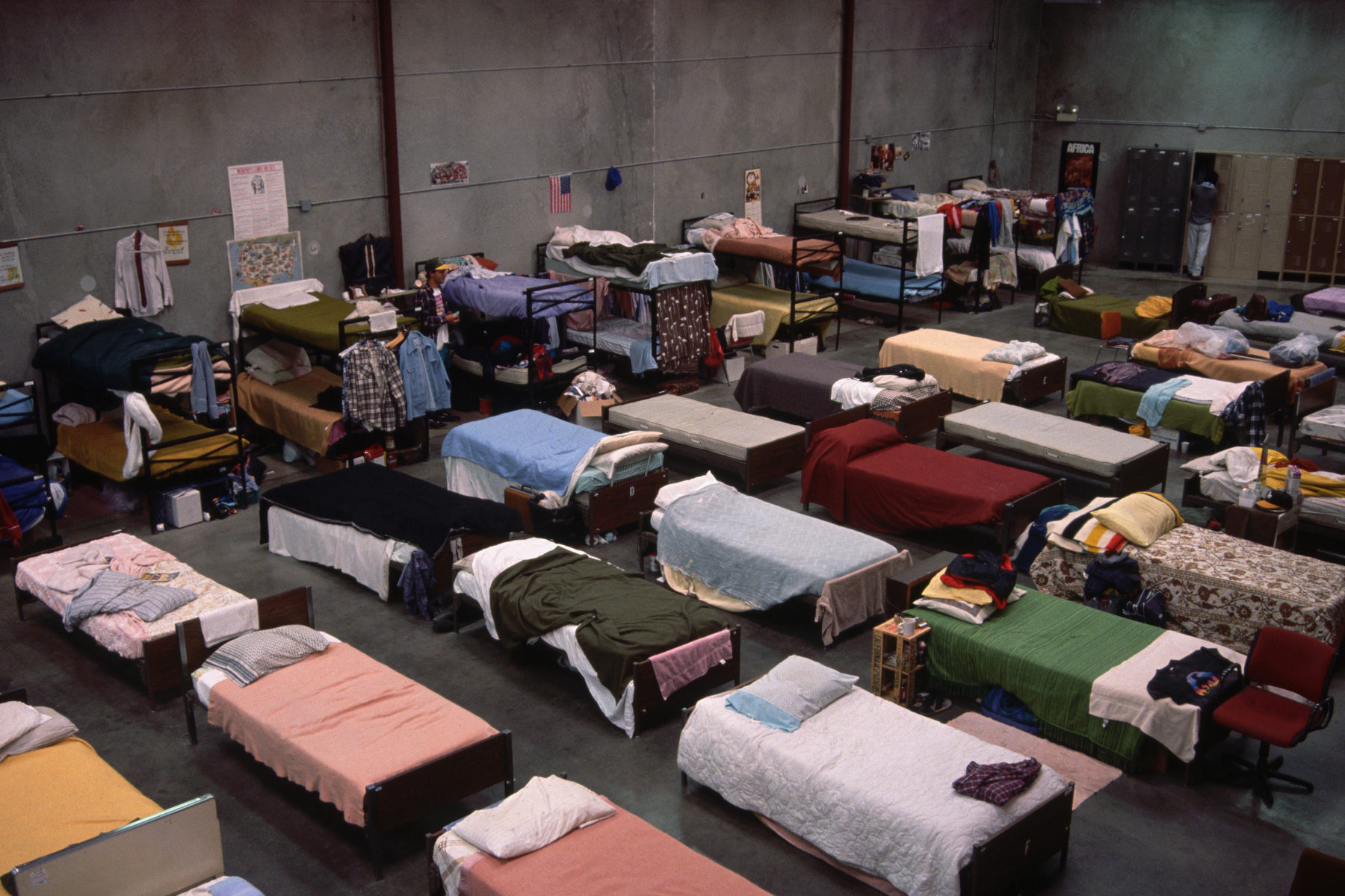 Rows of beds line up in a massive shelter for unhoused people.