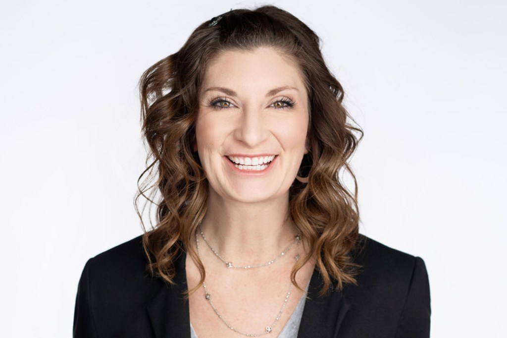 A woman smiles at the camera against a white background.