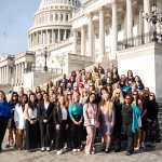 A group of people stand on the steps of Capitol Hill for a group photo.