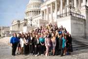 A group of people stand on the steps of Capitol Hill for a group photo.