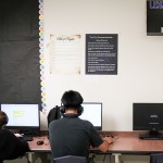 Two students work at computers with posters of the Bill of Rights and Ten Commandments hanging above their heads.