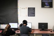 Two students work at computers with posters of the Bill of Rights and Ten Commandments hanging above their heads.