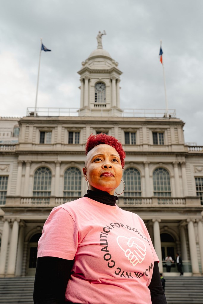 Allison Julien stands outside New York City Hall wearing a pink Coalition for Domestic Workers shirt.