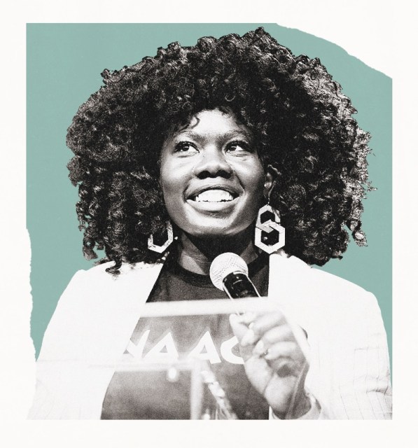 Black and white image of a smiling woman speaking at a microphone against a teal background.