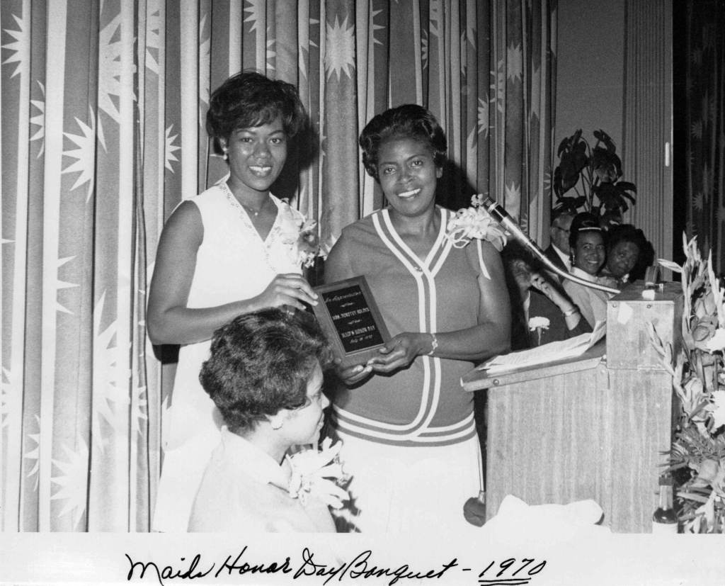 Dorothy Bolden and another woman hold a plaque at a Maid's Honor Day banquet in 1970.