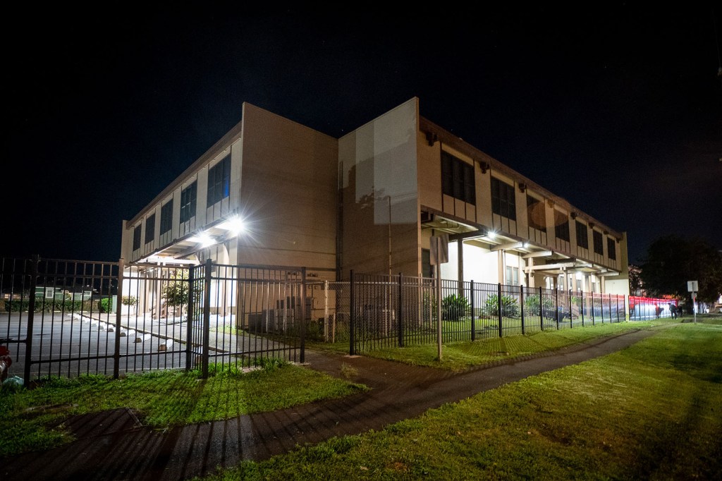 A nighttime exterior photo shows a medical office building behind a black metal fence.
