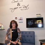 A woman sits on a blue bench in a care clinic waiting area beneath wall text reading, “Come to me & I will give you rest.”