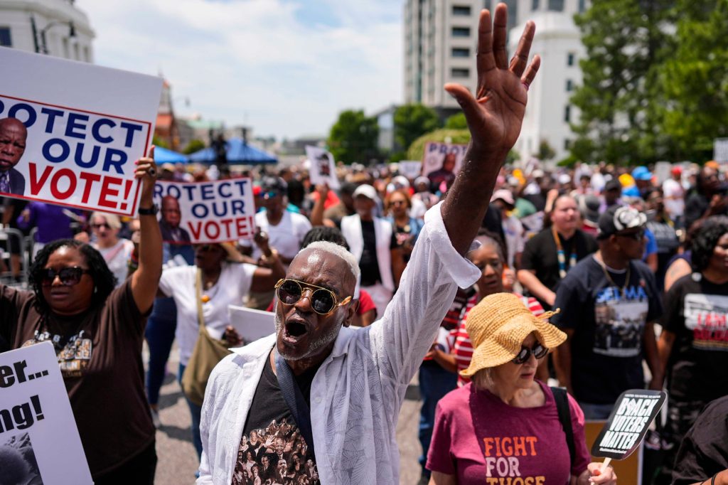 A crowd of protestors carrying signs about voting rights.