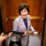 A woman smiles at reporters trying to interview her while she steps into an elevator.