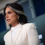 Tulsi Gabbard, in a white blazer speaks at a podium at the White House briefing room.