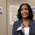 Gubernatorial candidate and former mayor of Atlanta, Keisha Lance Bottoms, speaks to supporters and members of the media. Behind her, a map of Georgia and campaign posters are seen in the background.