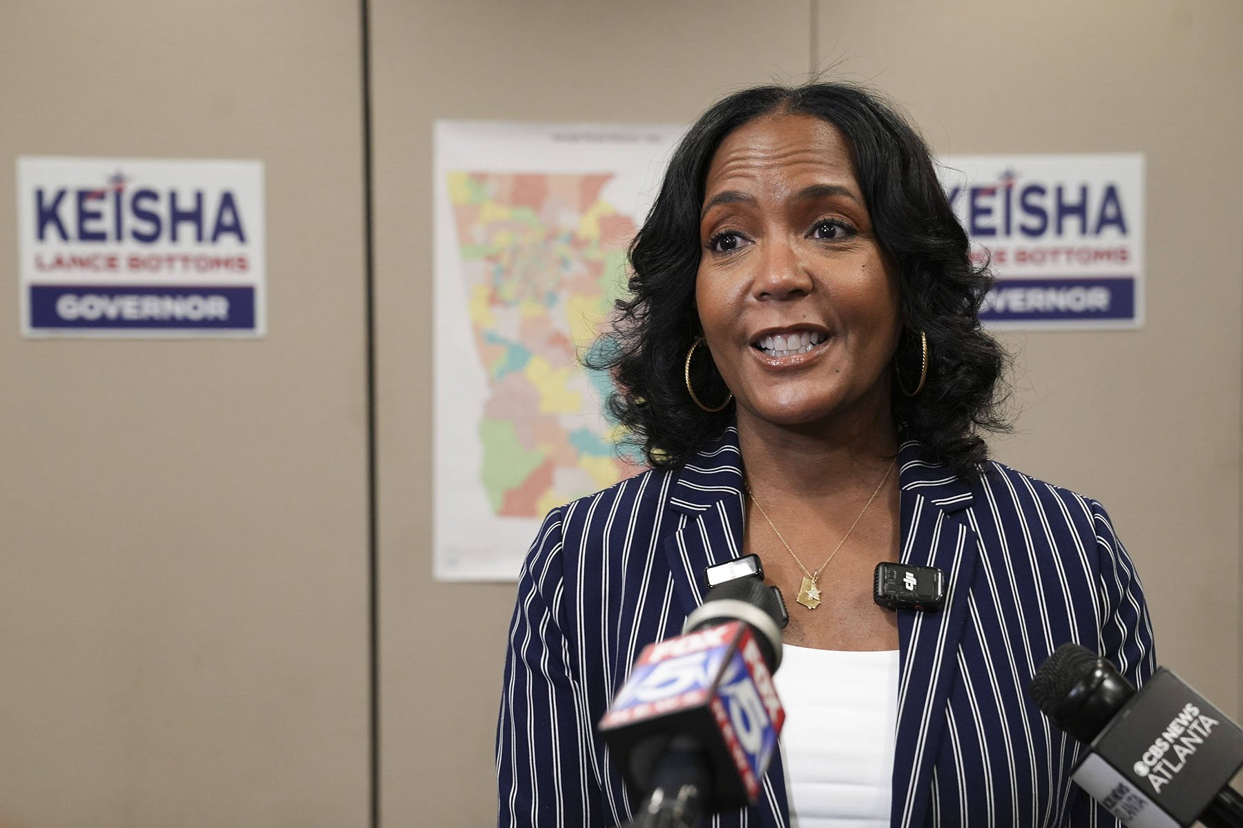 Gubernatorial candidate and former mayor of Atlanta, Keisha Lance Bottoms, speaks to supporters and members of the media. Behind her, a map of Georgia and campaign posters are seen in the background.