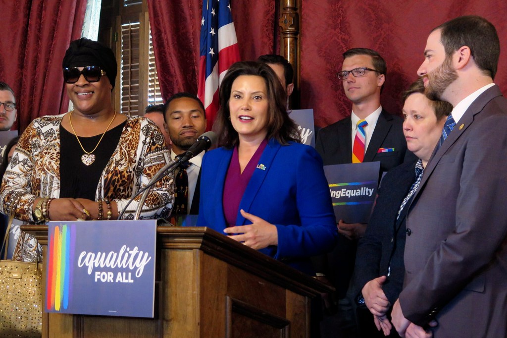 Jeynce Poindexter stands beside Michigan Gov. Gretchen Whitmer and lawmakers at a podium with an “equality for all” sign in the Michigan Capitol.