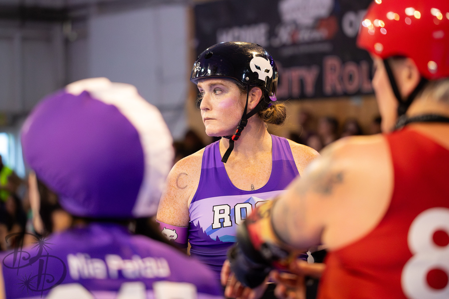 A derby player looks off to the side with a serious face, flanked by other players in the foreground.