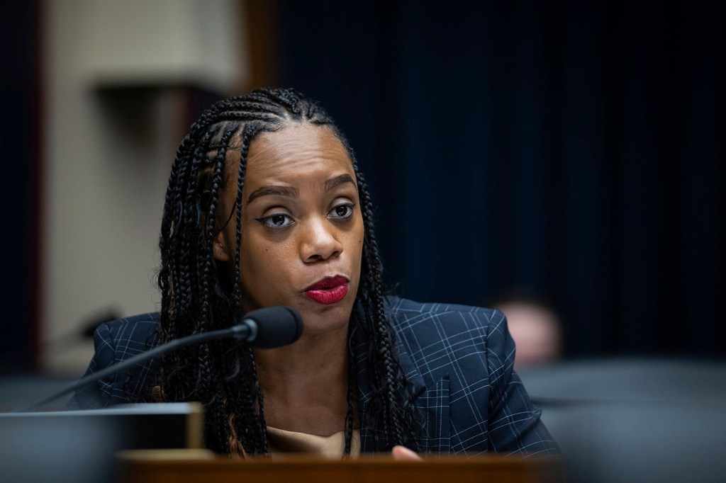 Rep. Summer Lee speaks into a microphone during a congressional hearing. She wears a plaid blazer and red lipstick.