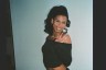 Swan smiles while posing in a black off the shoulder top.