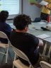 A seated person seen from behind listens to a family preparedness presentation