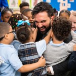 A group of preschoolers in uniforms hug New York Mayor Zohran Mamdani.