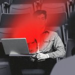 A black and white photo illustration of a male student sitting in auditorium seating with a laptop, partially obscured by a bright red flare across the center of the image coming from his computer screen.
