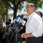 Xavier Becerra speaks into multiple microphones