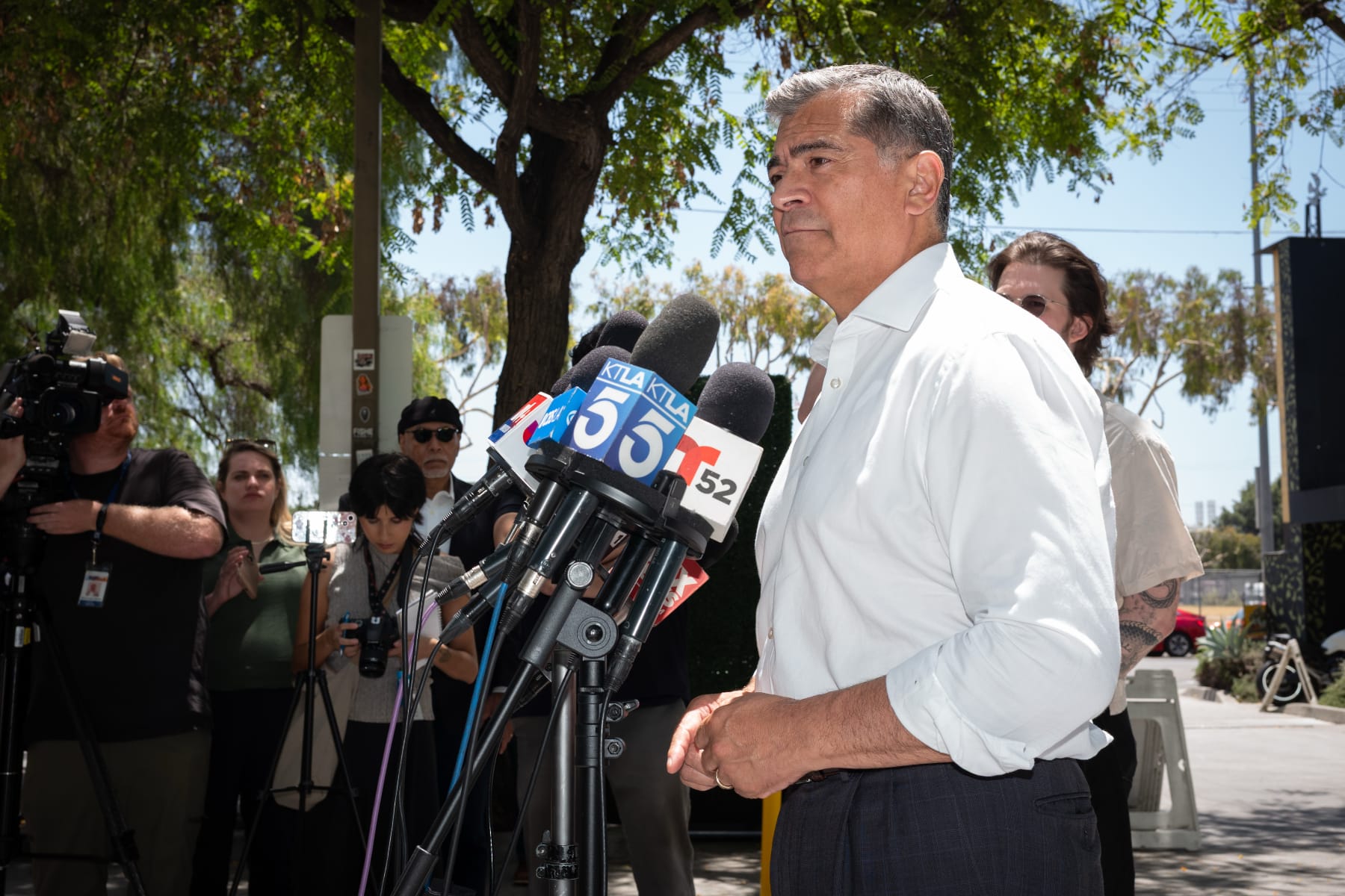 Xavier Becerra speaks into multiple microphones
