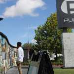 A large outdoor sign for Pulse nightclub is to the right, to the left is a wall with lots of images and a man standing looking at them